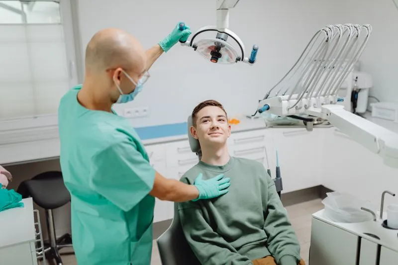 A dentist in scrubs talking with a patient in the chair